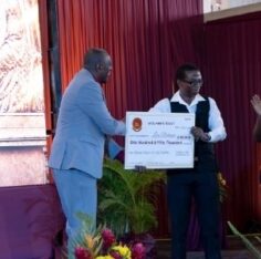 Leon Robinson receives a ceremonial cheque for JA$150,000 for first place in the 300th anniversary logo competition.