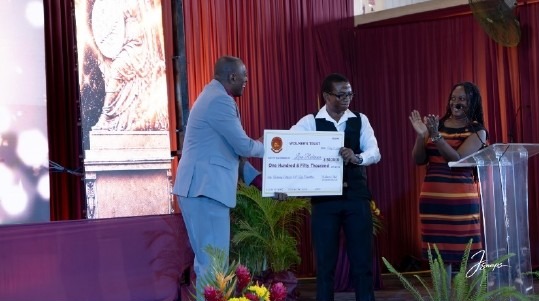 Leon Robinson receives a ceremonial cheque for JA$150,000 for first place in the Wolmer’s Trust 300th anniversary logo competition.