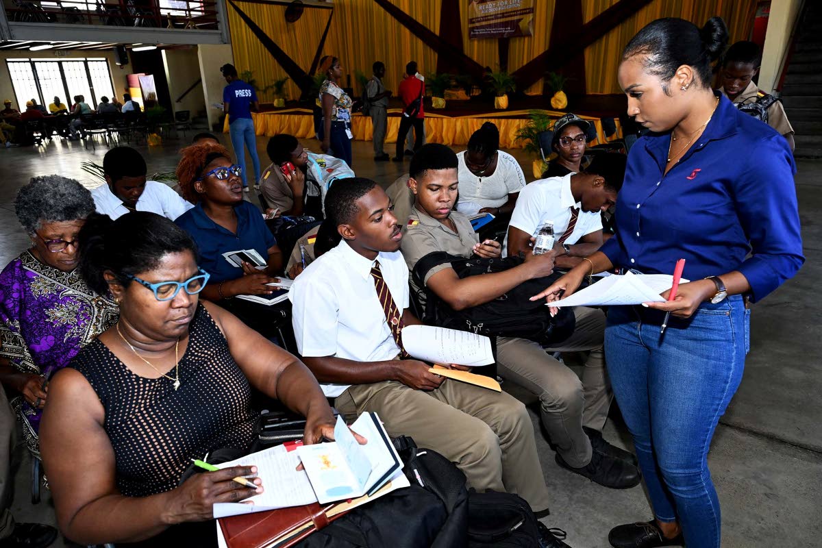 Monae Morgan, personal banking officer of Scotiabank, handing documents to students at Ready For Life. Photo: Jamaica Gleaner, 4 May 2024.