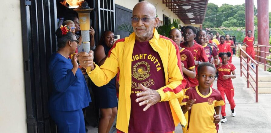 Douglas Orane takes the torch to Principal Dwight Pennycooke on Wolmer’s Day 2026. Photo: Garfield Robinson / Jamaica Observer