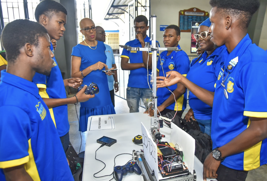 Students gathered around a robot. Caribbean National Weekly and NY Carib News published this photograph with their reports of 24 and 23 September 2026. Neither report printed a caption or a photo credit.
