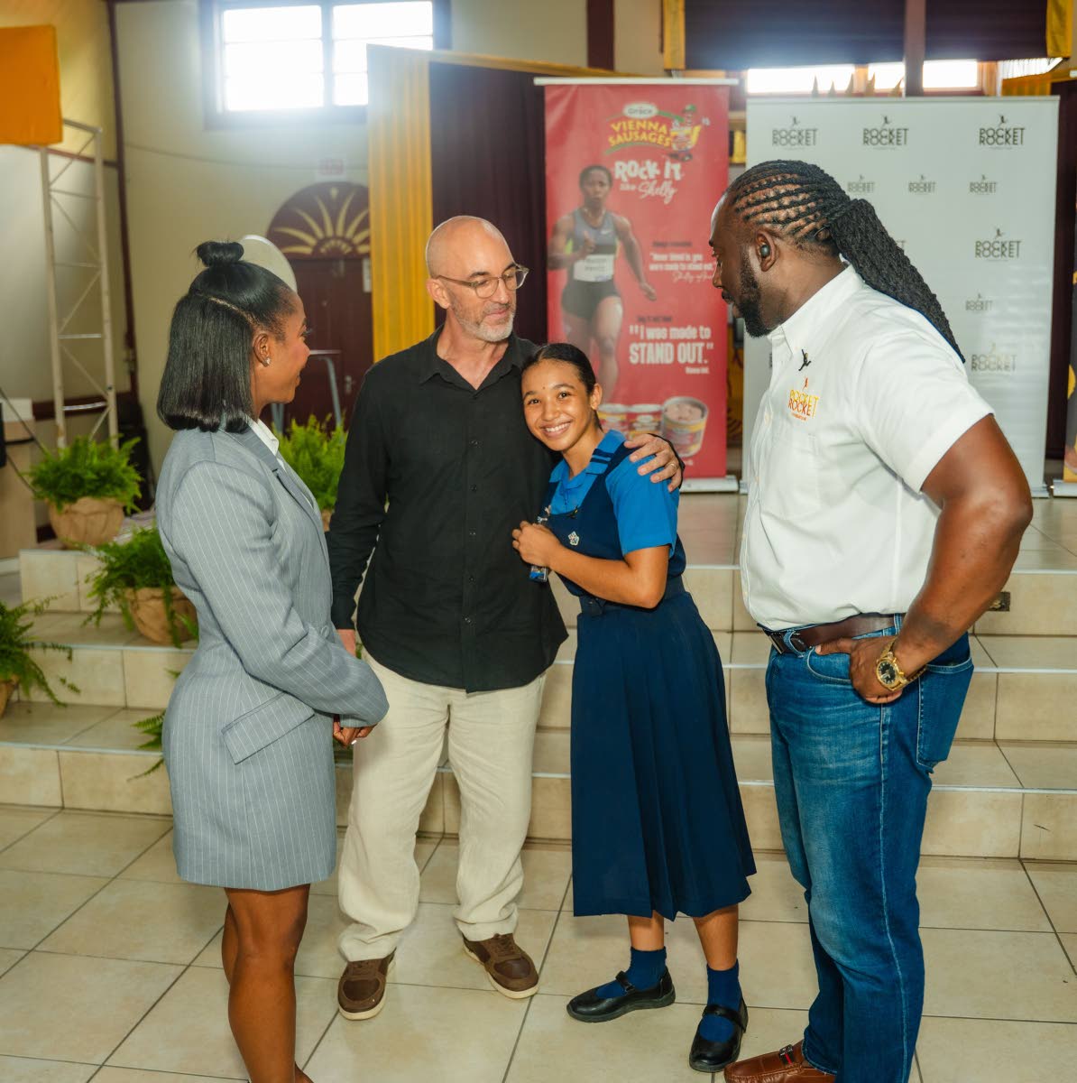 Jazmyne Wilkinson hugs her father, Gregory Wilkinson (second left), as she smiles for the lens. They are joined by Shelly-Ann Fraser-Pryce, founder and chairwoman of the Pocket Rocket Foundation, and Dr Jermaine McCalpin, executive director of the Pocket Rocket Foundation, at the foundation’s recent awards ceremony. Photo - Contributed Jamaica Gleaner, October 3, 2026.