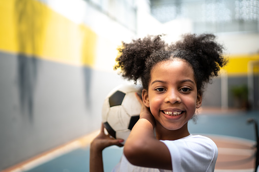 Portrait of a happy girl holding a soccer ball during physical activity class